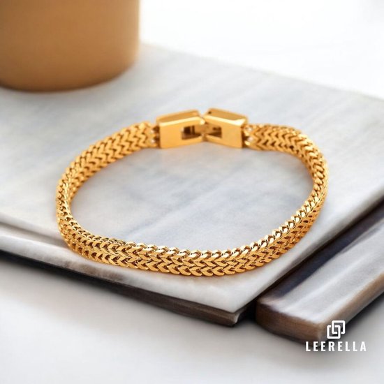 Gouden schakelarmband met dubbele rij schakels en rechthoekige gesp, op marmeren ondergrond.