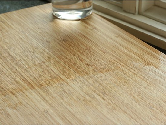 Houten snijplank met linnenneren en een glas water.