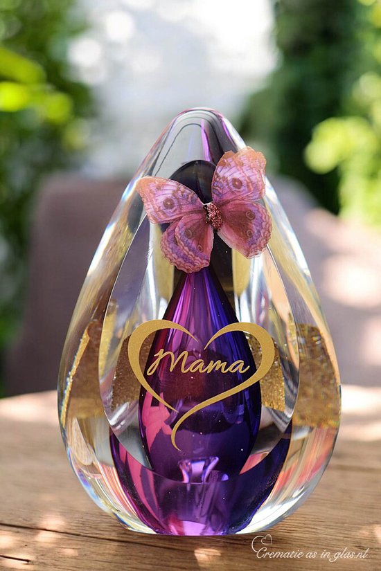 Glazen druppelvormige urn met paarse kern, vlinder en gouden hart met 'Mama'.