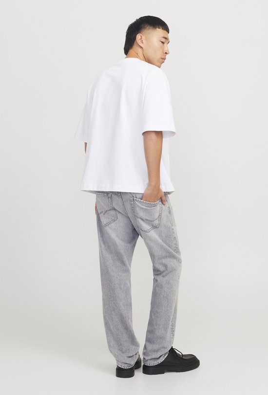 Man met witte T-shirt en grijze jeans, gedraaid.