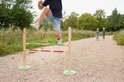 Jongen springt over houten hindernisbaan met rode en groene balken, op een bospad.