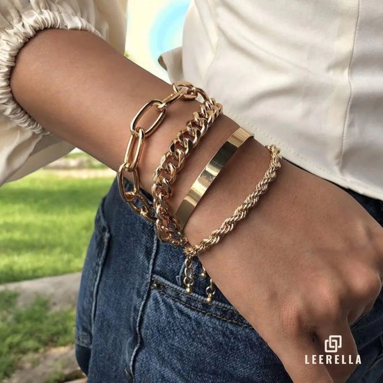 Gouden armbandenset met ovale schakels, een gladde band, een dikke schakelketting en een gedraaide schakelketting om een vrouwenpols.