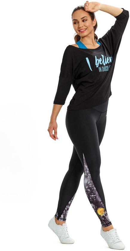 Model draagt zwart shirt met 3/4 mouwen en tekst "I believe IN CHOCOLATE", en een zwarte legging met grijze, witte en gele print.