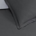 Detail van de hoek van een antracietkleurige kussensloop met grijze rand.