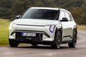 Lichtgroene Kia EV electric SUV rijdt op een weg.
