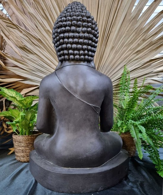 Achterkant van een zwart Boeddhabeeld in meditatiehouding, zittend op een sokkel.