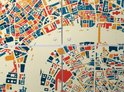 Gros plan d'une carte de la ville de Londres, divisée en carrés, avec des bâtiments en bleu, orange et rouge sur fond crème.