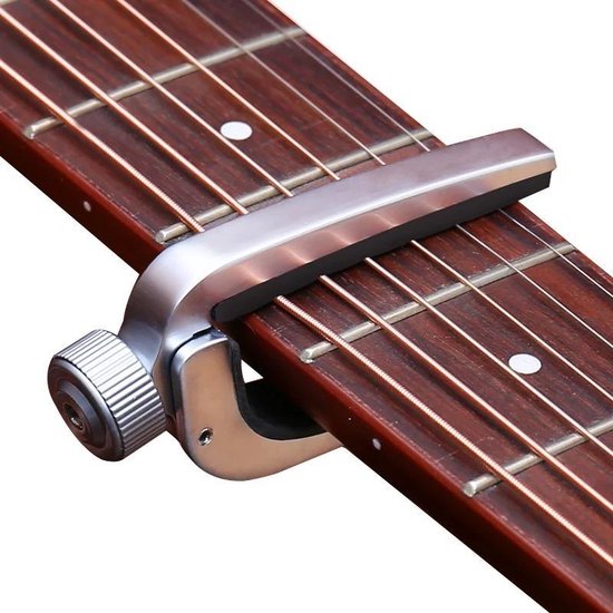 Zilverkleurige gitaarkapodaster met draaiknop op de hals van een gitaar.