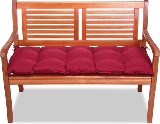 Rood gestoffeerd bankkussen op een houten tuinbank.