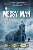 Boekomslag van 'The Messy Man', met een verlaten kerk en een figuur aan de zijkant, vogelzwermen vliegen over een sombere hemel. Titel 'The Messy Man'.