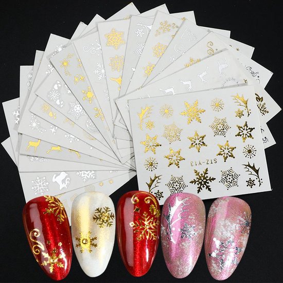 Collectie van kunstnagels met gouden en zilveren winterse nail art, naast vellen met stickers.