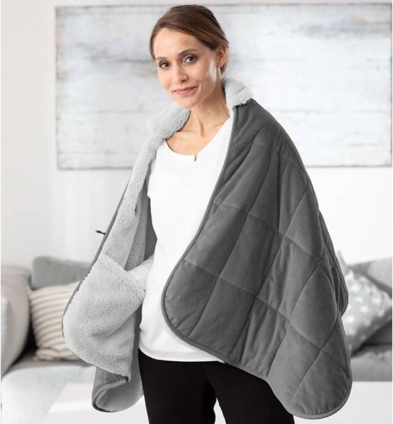 Vrouw staand, draagt een grijze gewatteerde deken met zachte witte teddy voering, met open handwarmers.