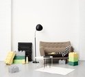 Woonkamer met grijze bank, zwarte vloerlamp en LEGO opbergdozen in geel, groen en grijs.