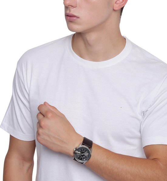 Jonge man met witte T-shirt draagt een zilverkleurig Diesel horloge met donkerbruine leren band om zijn pols.
