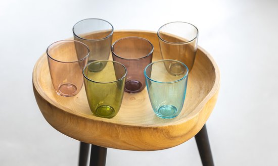 Six verres colorés (ambre, vert, violet, bleu, gris, transparent) dans un bol en bois.