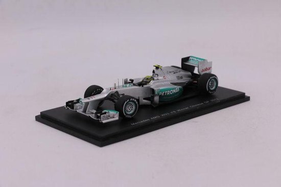 Zilveren F1-auto met groene PETRONAS-logo's, op een zwarte standaard.