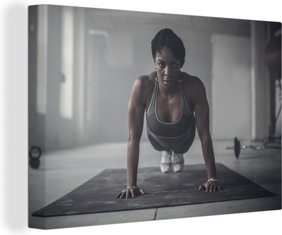 Canvas Schilderij Een vrouw die push ups in donkere sportschool doet - 60x40 cm - Wanddecoratie