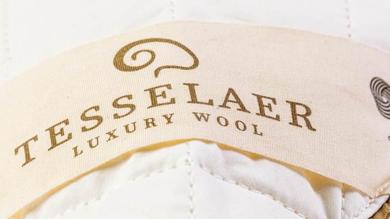 Close-up van het Tesselaer Luxury Wool label op de witte wollen onderdeken.