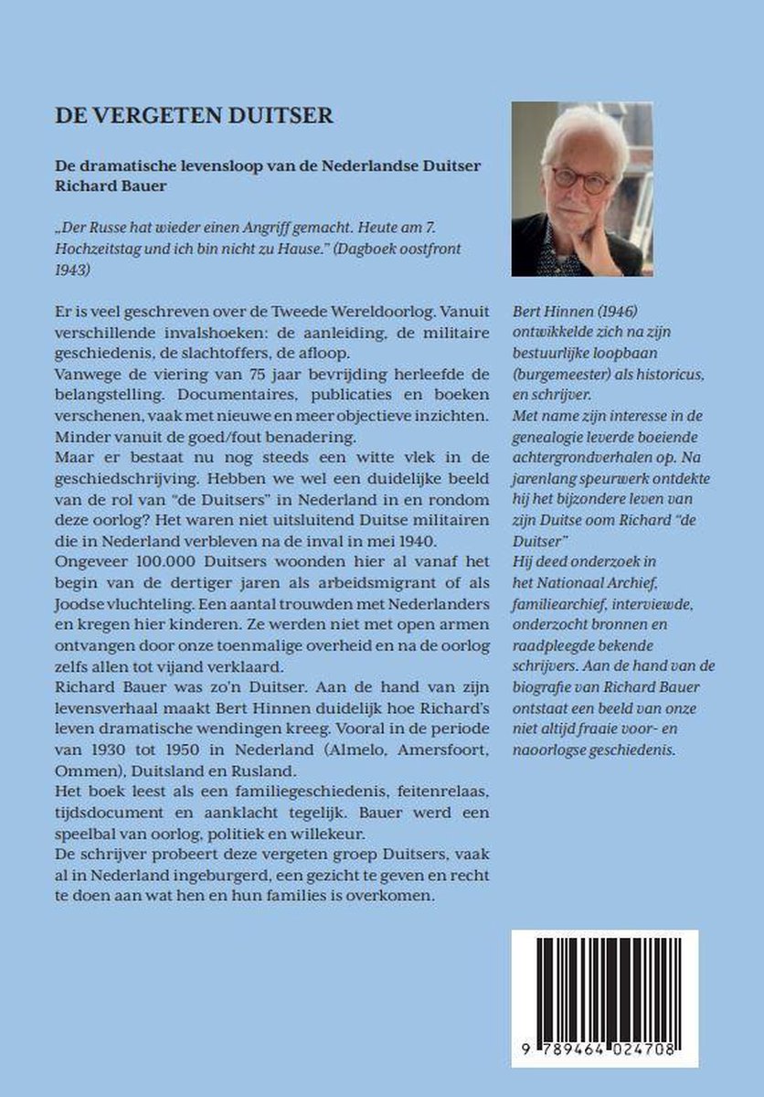 Foto van een oudere man met bril, zittend, een boek in zijn hand, tegen een witte achtergrond.