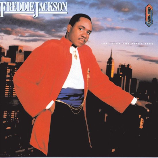 Freddie Jackson in een oranje jas, wit overhemd en zwarte broek voor een stadsgezicht.