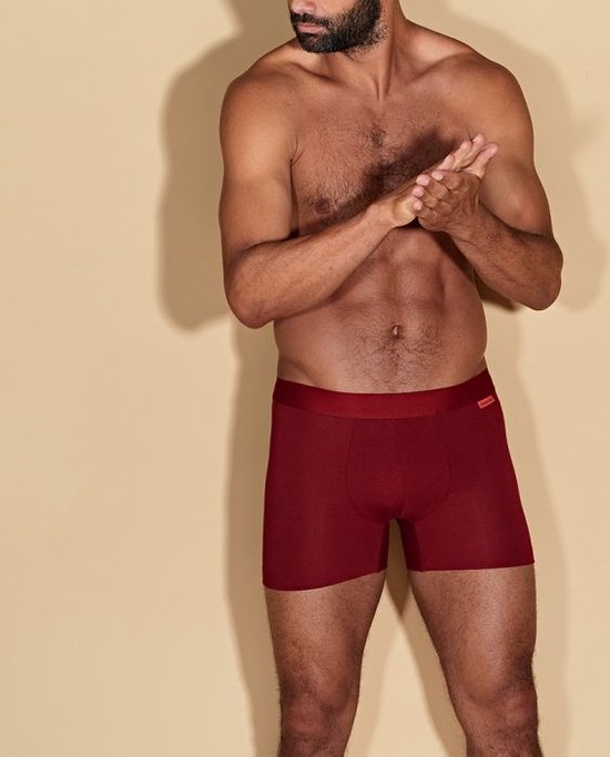 Man met baard, zittend, met rode boxershort aan.