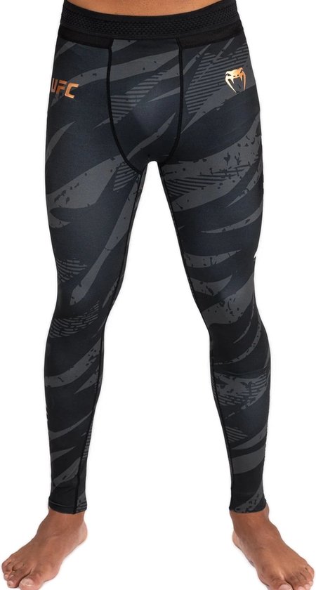 Zwarte sportlegging met grijs abstract patroon, koperkleurig UFC-logo en VENUM-slanglogo.
