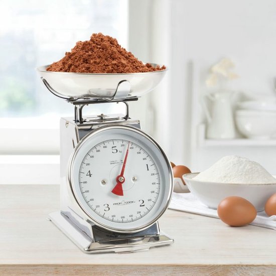 Zilverkleurige keukenweegschaal met een RVS schaal gevuld met bruine poeder, witte wijzerplaat, rode wijzer, en een weegbereik van 5 kg.