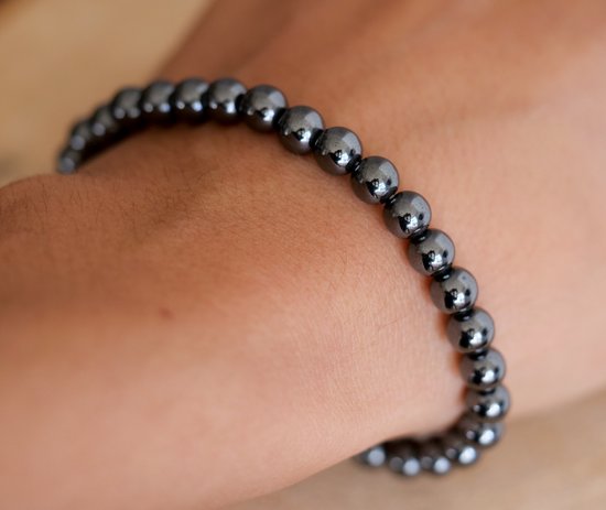 Zwarte, glanzende hematiet kralenarmband om een pols.
