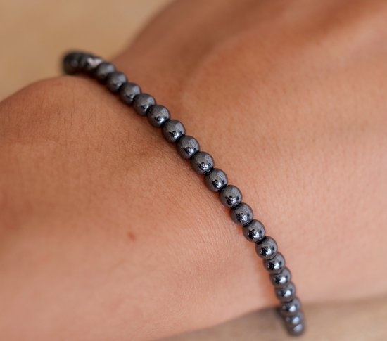 Dunne, donkergrijze hematite kralen armband gedragen om een arm.
