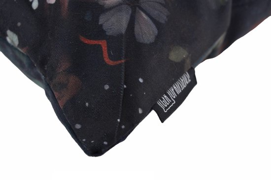 Detail van de hoek van een kussen met donkere bloemenprint en de merklabel.
