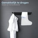 Gedroogde witte badjas hangt aan een zwarte haak. Een witte douchehoes voor been hangt ernaast.