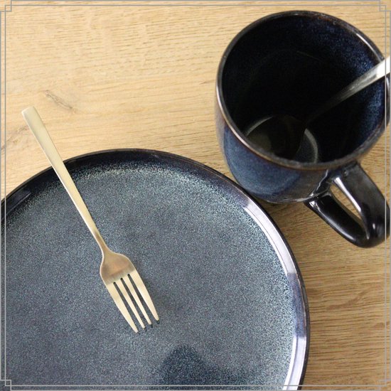 Blauwgroene mok en schotel met gouden vork en lepel, op houten tafel.