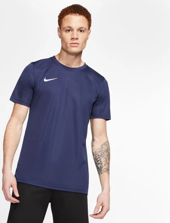 Man met rood haar draagt een donkerblauw Nike sportshirt met een wit logo op de borst. Zwart afgezet.
