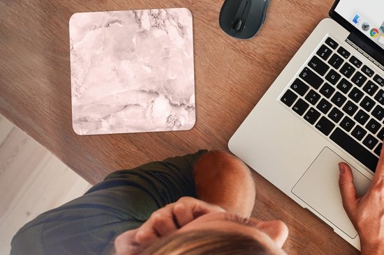 Roze marmeren muismat op een houten bureau, naast een laptop en muis.