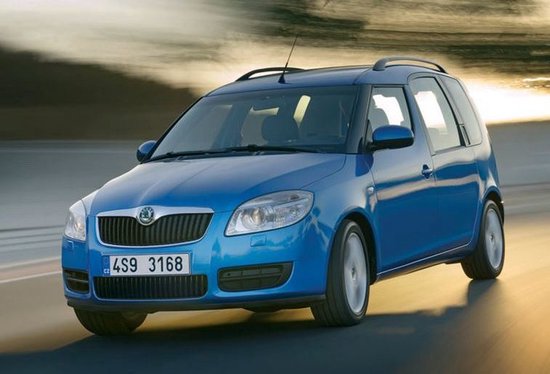 Blauwe Skoda Roomster rijdt op een weg tijdens zonsondergang.