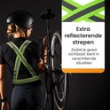 Vrouw met fiets en helm, draagt een geel reflecterend sportvest met brede reflecterende strepen.