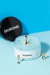 Open pot hyaluronzuur masker met miniatuurfiguren die op de gel surfen. Zwart deksel ernaast.