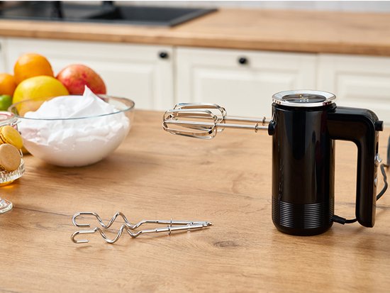 Zwarte handmixer op een houten aanrecht naast een kom met eiwit. Gardes naast de mixer.