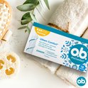 Ob ProComfort Normal tampons op een witte handdoek, met loofah en planten. De verpakking toont een witte tampon met blauwe bloemen.