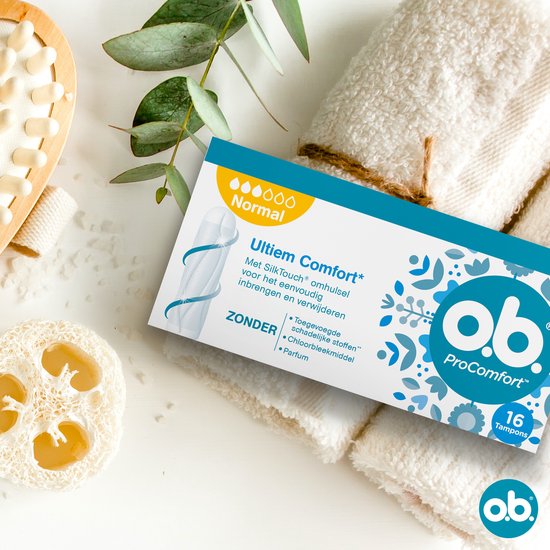 Ob ProComfort Normal tampons op een witte handdoek, met loofah en planten. De verpakking toont een witte tampon met blauwe bloemen.