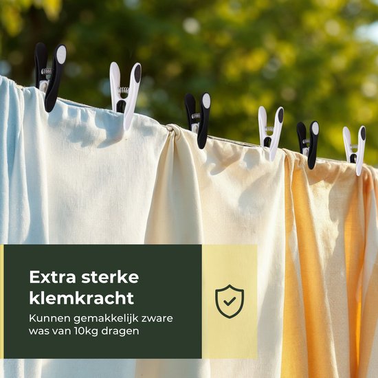 Witte, lichtblauwe en gele stoffen hangend aan een waslijn, vastgehouden door zwarte en witte knijpers.