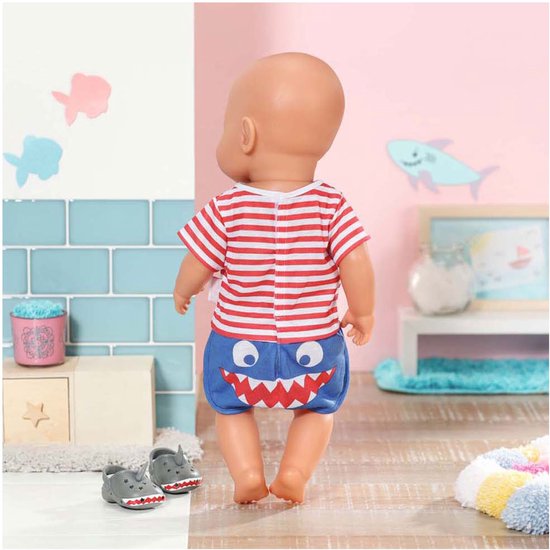 Baby Born pop van achteren gezien, met rood-wit gestreept shirt en blauwe broek met haaientanden. Draagt grijze haaienschoentjes.