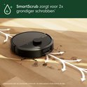 Zwarte robotstofzuiger met SmartScrub dweilt een houten vloer met vlekken.