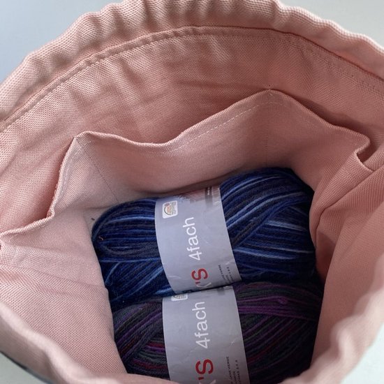 Gedetailleerde projecttas met roze binnenzijde, twee vakjes, en twee bollen blauwe en paarse wol.
