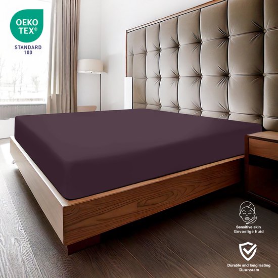 Drap-housse violet foncé sur un lit fait avec une tête de lit.