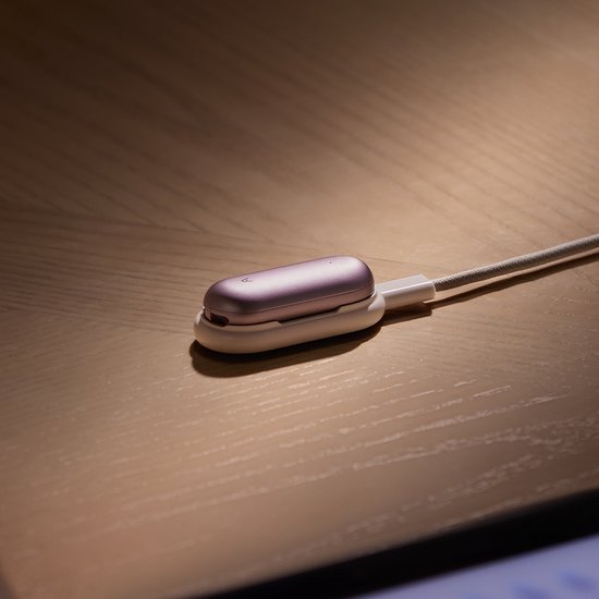Paars PLAUD NotePin-apparaat op een houten tafel, aangesloten op een oplaaddock met kabel.