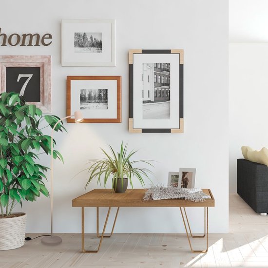 Beige staande lamp met een gebogen arm, naast een houten bankje met planten.