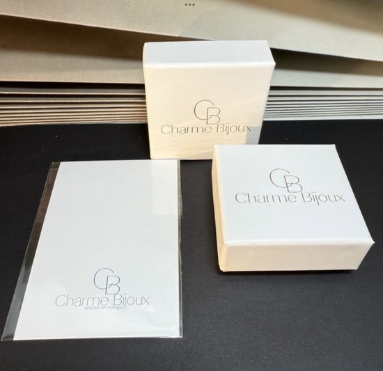 Twee witte Charme Bijoux geschenkdozen en een beschermhoes.