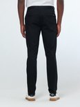 Man van achteren in zwarte chino met twee achterzakken en witte sneakers.