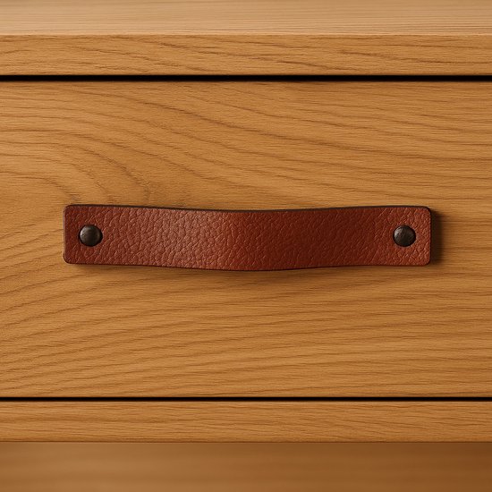 Bruine leren handgreep met zwarte knoppen op een houten lade.